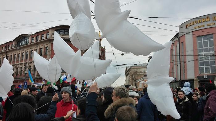 Man sieht Luftballons in Taubenform in einer Menschenmenge