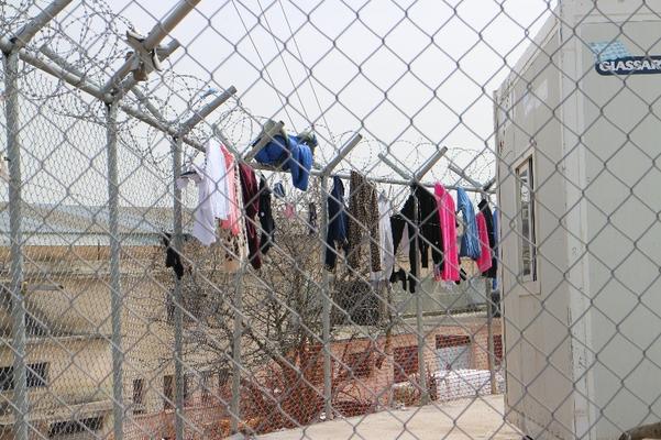 Kleider hängen zum trocknen an einem Gitter mit Stacheldraht um das Lager Vial