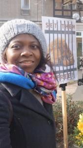 Millicent Adjei vor einem Schild mit der Aufschrift &quot;Set them free&quot;