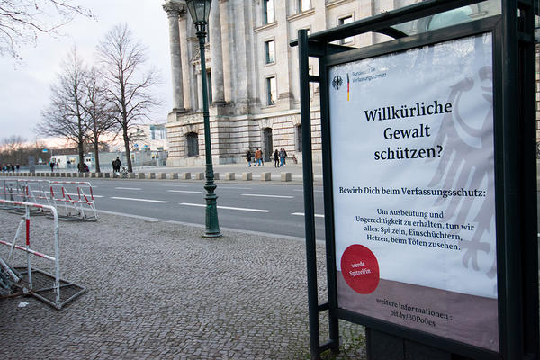 Ein Beispiel für Adbusting: Ein umgestaltetes Werbeplakat des Bundesamts für Verfassungsschutz liest sich: &quot;Willkürliche Gewalt schützen? Bewirb dich beim Verfassungsschutz. Um Ausbeutung und Ungerechtigkeit zu erhalten tun wir alles&quot;