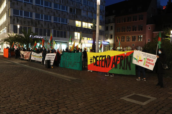 Reihe von Demontrant*innen, die Transparente halten, auf denen unter anderem &quot;Defend Afrin&quot; und &quot;Fight for Rojava&quot; steht.