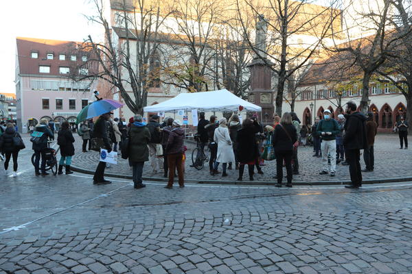 Eine Gruppe von Menschen sammelt sich um einen weißen Pavillion.