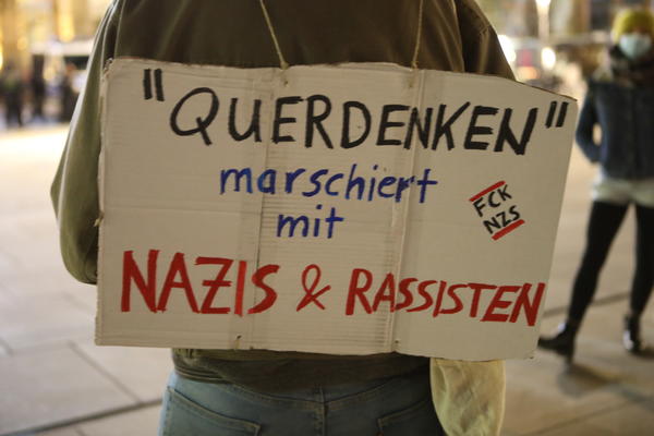 Ein Schild auf dem steht: &quot;&#039;Querdenken&#039;&quot; marschiert mit Nazis &amp; Rassisten&quot;.