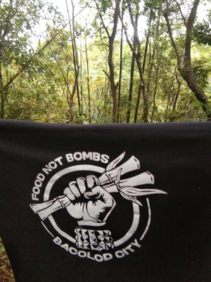 Banner &quot;Food not Bombs - Bacolod City&quot;, im Hintergrund Wald