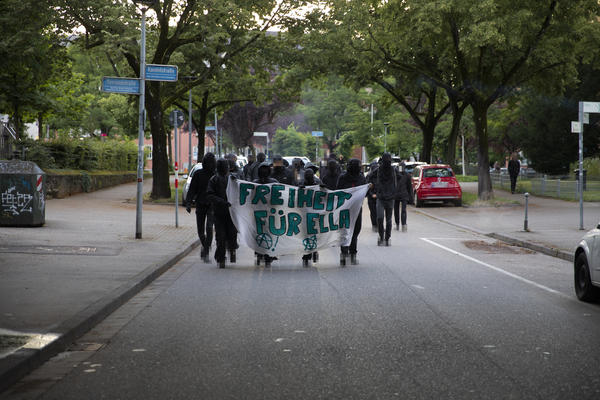 Eine Demofront mit weißem Transparent, auf dem in grünen Buchstaben &quot;Freiheit für Ella&quot; steht.