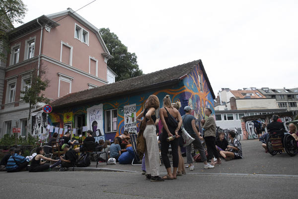 Mehrere Dutzend Menschen stehen vor dem bunten Häuschen in der Gartenstraße 19 und halten eine Kundgebung ab.