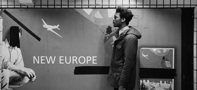 Schwarzer Mann vor einem lebensgroßen Plakat. &quot;New Europe&quot; Foto von Johny Pitts in Schwarz-Weiß