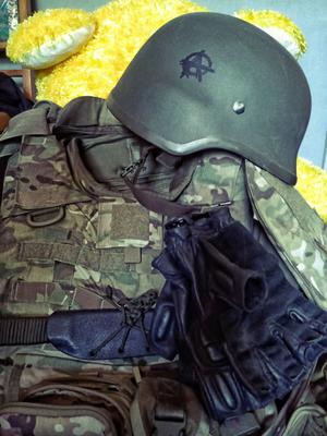Militärische Kampfuniform und Helm mit Anarchie-Symbol darauf.