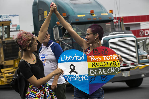 Zwei Frauen halten sich während eines Gay Pride Marches in Nicaragua an den Händen. Zusammen halten sie ein Plakat in Regenbogenfahnen, in dem Freiheit, Respekt und Rechte für LSBTI gefordert wird.