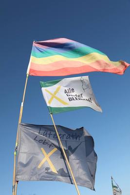 Verschiedene Flaggen im Wind, unter anderem Alle Dörfer bleiben, Lützerath lebt und Pride Flage