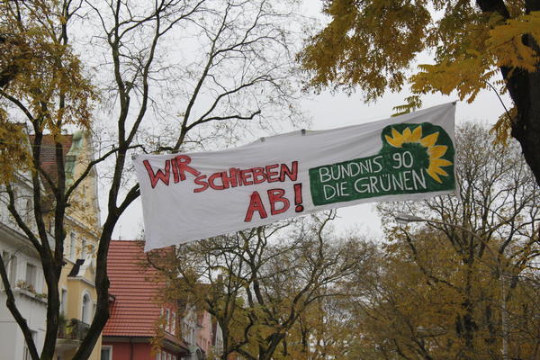Transparent neben Aktion vor Freiburger Grünen Büro mit dem Logo der Partei Bündnis 90/ Die Grünen und dem Slogan Wir schieben ab.