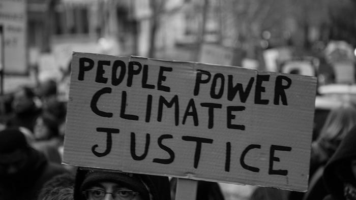 Eine Person, die ein Schild mit der Aufschrift &quot;People Power - Climate Justice&quot; hochhält