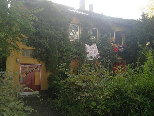 Besetztes Haus, überwuchert mit Efeu, Banner und Flaggen hängen aus den Fenstern