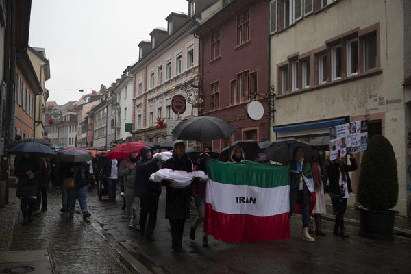 Demonstrationszug mit Iranfahne und Schirmen in der Freiburger Altstadt.