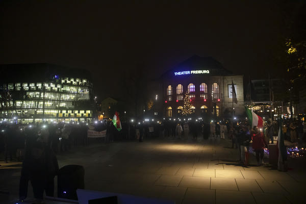 Auf dem Platz der Alten Synagoge werden im Dunkeln Lichter von den Handys der Demonstrierenden geleuchtet. Im Hintergrund die UB und rechts mittig das Stadttheater.