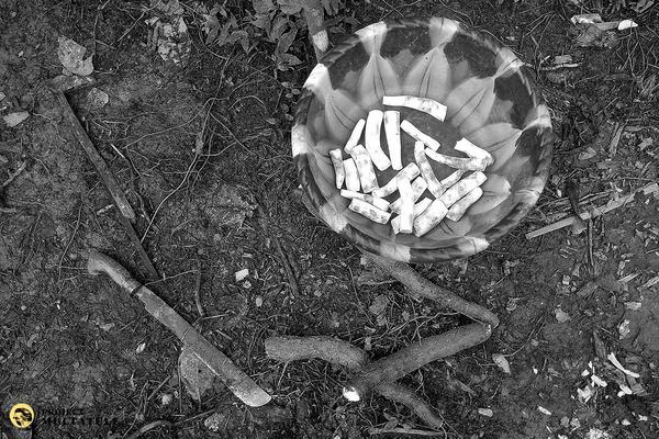 Eine Schüssel mit geschälten Yamswurzeln, daneben eine Machete und einige noch ungeschälte Wurzeln liegen am Boden