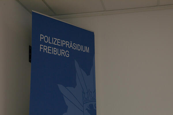Blauer Aufsteller vor weißer Wand: Polizeipräsidium Freiburg