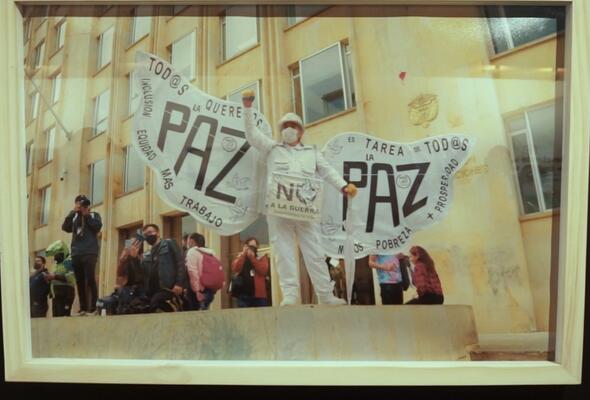 Foto in einer Ausstellung in Bogotá - Frau mit weißen Flügeln, darauf steht: Paz (Frieden)
