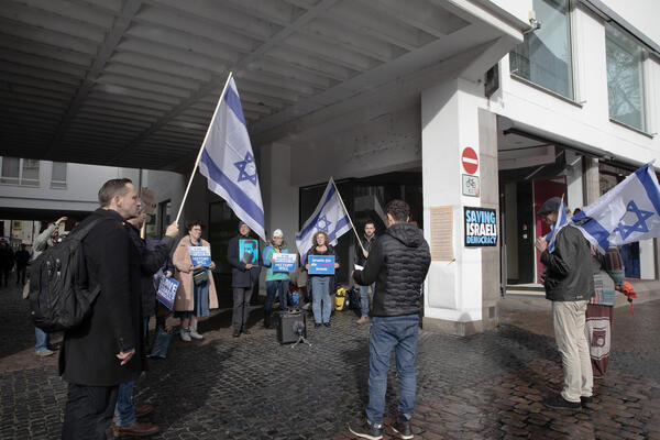 Eine Gruppe von Menschen steht im Kreis, einige von ihnen tragen Israel-Fahnen. An einer Säule der Unterführung ist ein Plakat angebracht: &quot;Saving israeli democracy&quot;