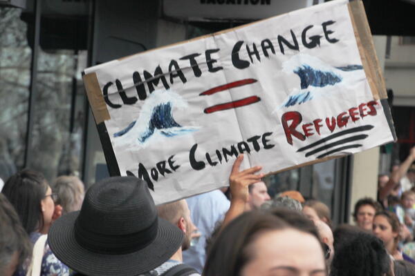 Protestschild mit der Auffschrift Climate Change = more Climate Refugees