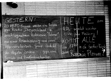 Schwarweiss Bild einer Tafel in einer Schule 1985. Bekannt gemacht wird eine Razzia und ein RazziaPlenum