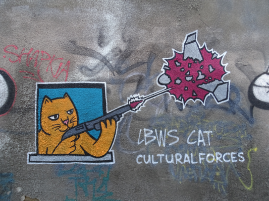 Wandgraffiti einer Katze, die aus dem Fenster mit einer Schrotflinte eine russische Schahed-Drohne abschießt..