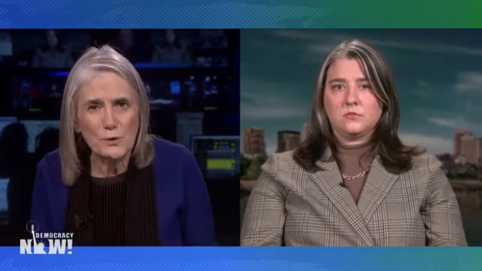 Amy Goodman und Abbey Crain im Interview: Split Screen bei Democracy Now! Amy sitzt vor Bildschirmen und Abbey vor einer Skyline