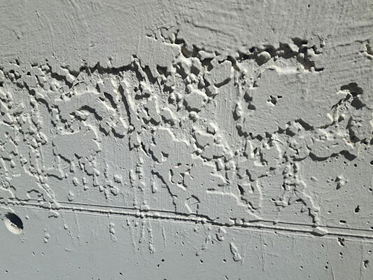Fotografie eines Ausschnitts einer Außenwand mit klecksigem Putz.
