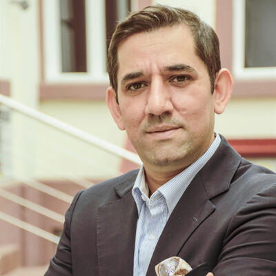 Jovica Arvanitelli auf der Website des Landesverbands Deutsche Sinti und Roma: Er trägt Anzug und Einstecktuch, blickt freundlich in die Kamera. Im Hintergrund ist der Innenhof des Kulturzentrums Romno Kher in Mannheim zu sehen.