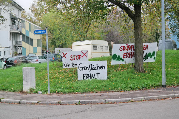 Wiesendreieck am Auggener Weg, das die FSB bebauen will. Darauf Protestschilder &quot;Grünflächen erhalten&quot; - im Hintergrund zu sehen Teile der Sinti-Siedlung