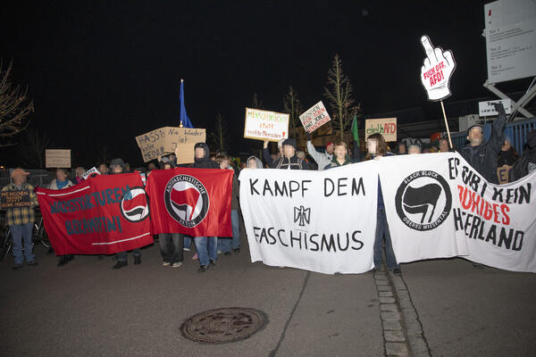 Mehrere Transparente und eine Antifa-Fahne sind als Demofront nebeneinander gereiht. Dahinter Menschen mit Schildern. U.a. ein Stinkefinder mit &quot;Fuck AfD&quot;.