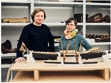 Ankündigung des Vortrags von Godwin Kornes, Ethnologe und Provenzienzforscher. Ein Foto von ihm und seiner Kollegin Stefanie Schien im Archiv mit einem Bootsmodell vor Regalen voller Objekte aus Ozeanien. 
