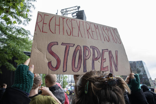 Pappschild mit roten Großbuchstaben: &quot;Rechtsextremismus stoppen&quot;