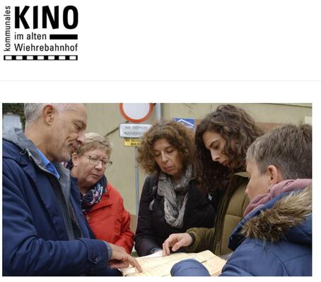 Still aus dem Film Mein Illegales LEben mit den Protagonist*innen, die sich auf der Straße über historische Dokumente beugen