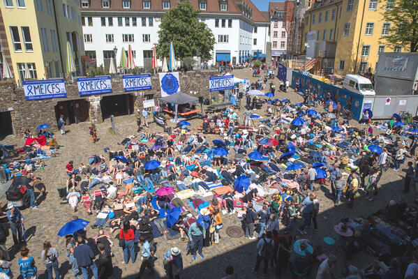Blick auf den Augustinerplatz von oben. Viele Leute liegen auf mitgebrachten Matten. Die Farbe blau dominiert auf vielen Shirts oder Schirmen der Initiative &quot;ME/CFS Freiburg&quot;.