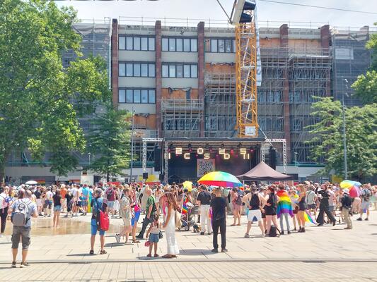 bunt gekleidete Menschen stehen vor der Bühne des CSDs