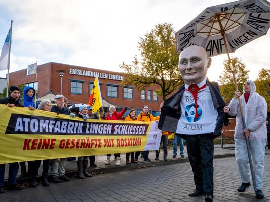 Ein Pappmaschee Putin-Kopf geht am Transpi Atomfabrik Lingen schliessen  beim rörterungstermin im November 2024 vorbei
