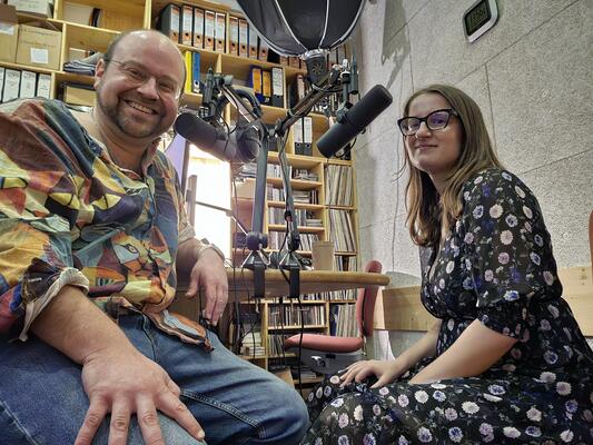 Thomas und kristina sitzen in einem Radiostudio an den Mikrofonen