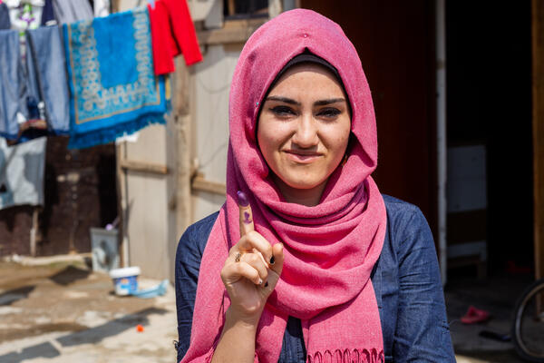 Im Mai 2018 gaben viele junge Menschen zum ersten Mal ihre Stimme ab. Im Rahmen des Iraq Elections Support Program führte Creative Associates International Wähleraufklärung durch und förderte die Wahlbeteiligung von Binnenvertriebenen und Minderheiten Junge Frau zeigt stolz die lila Stempelfarbe an ihrem Finger zur Signatur der Wahl