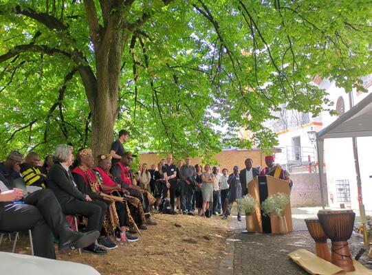 Bei einer Zeremonie in Freiburg wurde im Juli 2026 der Rückgabeprozess der Human Remains und die Rehumanisierung der verschleppten Maka aus Kamerun eingeleitet Gesellschaft der Zeremonie unter einem Baum bei den Reden