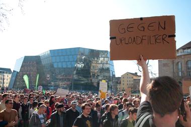 Hunderte Menschen demonstrieren vor der Uni-Bibliothek in Freiburg. Ein Mann hält ein Pappschild mit Aufschrift &quot;Gegen Uploadfilter&quot; hoch.