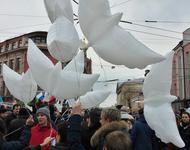 Man sieht Luftballons in Taubenform in einer Menschenmenge