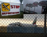 Hintergrund: Abgeschobene steigen unter Polizeibegleitung im Flugzeug der Bulgaria Air am 09.12.2014; Vordergrund: Transparente des Protests vor dem Terminal