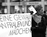 Eine Frau hält ein Schild, auf dem steht: Keine Gewalt an Frauen und Mädchen