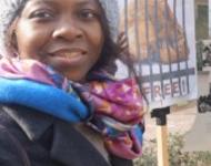 Millicent Adjei vor einem Schild mit der Aufschrift "Set them free"