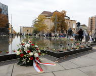 Ein Blumenkranz liegt vor dem Gedenkbrunnen der Alten Synagoge. An dessen Rand sind Blumen abgelegt.