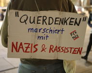 Ein Schild auf dem steht: "'Querdenken'" marschiert mit Nazis & Rassisten".