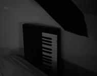 ein keyboard ragt hinter einem sofa hervor. das bild ist schwarz-weiß