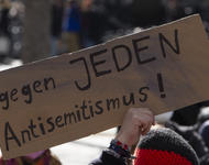 Bildausschnitt eines Schildes, das mit einer Hand in die Luft gehalten wird. Darauf steht: "Gegen jeden Antisemitismus!"