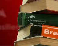 Bücherrücken gestapelt mit Brasilien und brasilieniniative und dem Logo, dem Gürteltier vor rotem Hintergrund